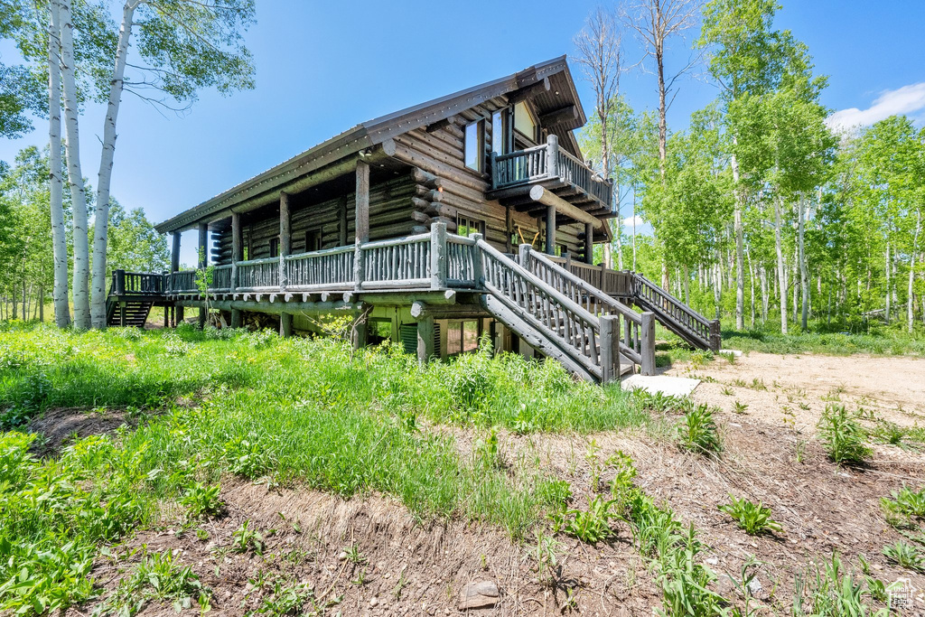View of side of home with log siding, stairway, and a wooden deck