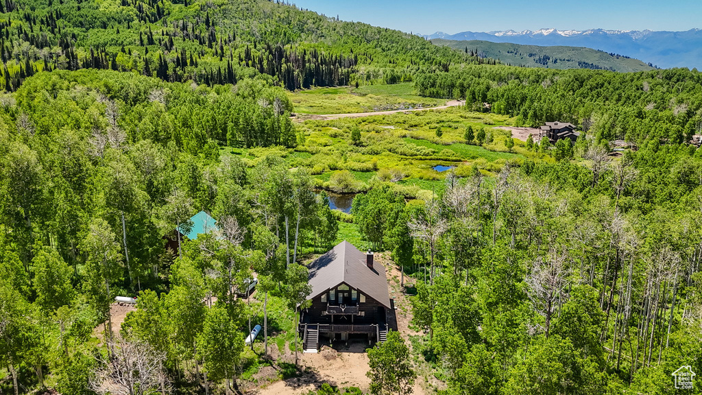 View from above of property with a heavily wooded area and a mountainous background