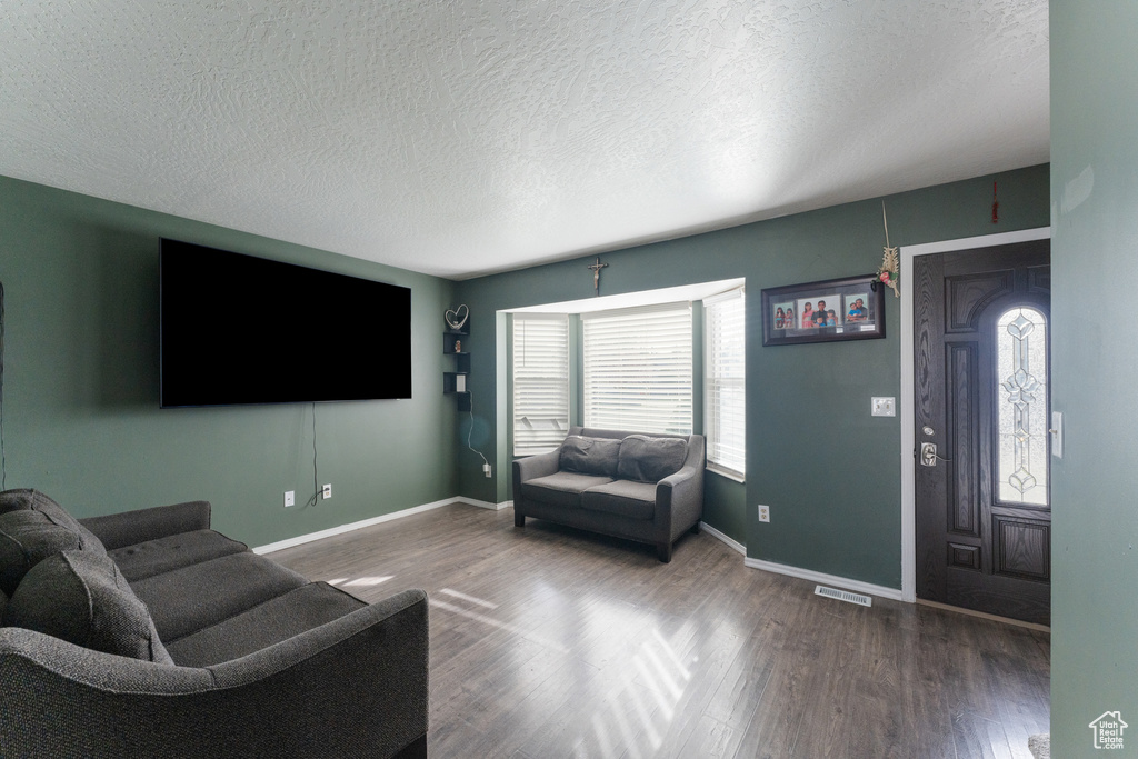 Living area featuring visible vents, baseboards, wood finished floors, and a textured ceiling