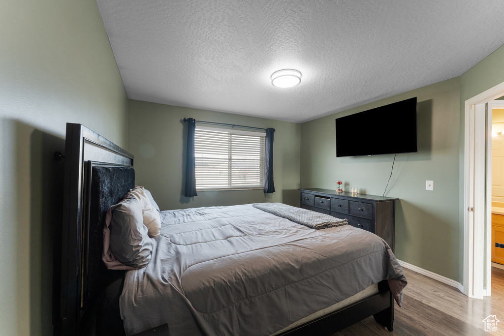 Bedroom with baseboards, a textured ceiling, and wood finished floors
