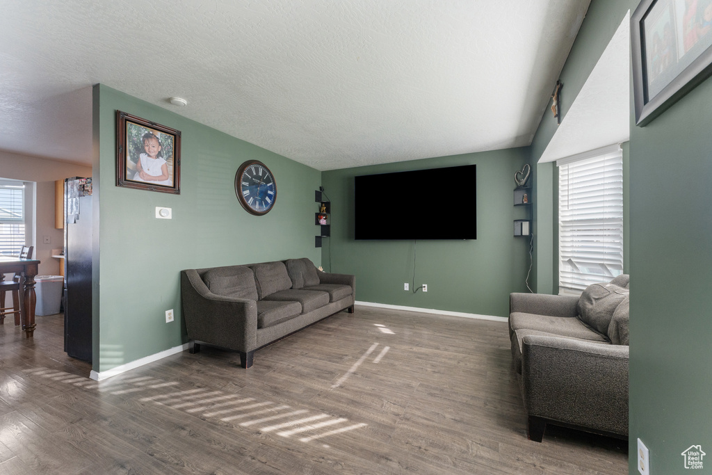 Living area featuring a textured ceiling, wood finished floors, and baseboards