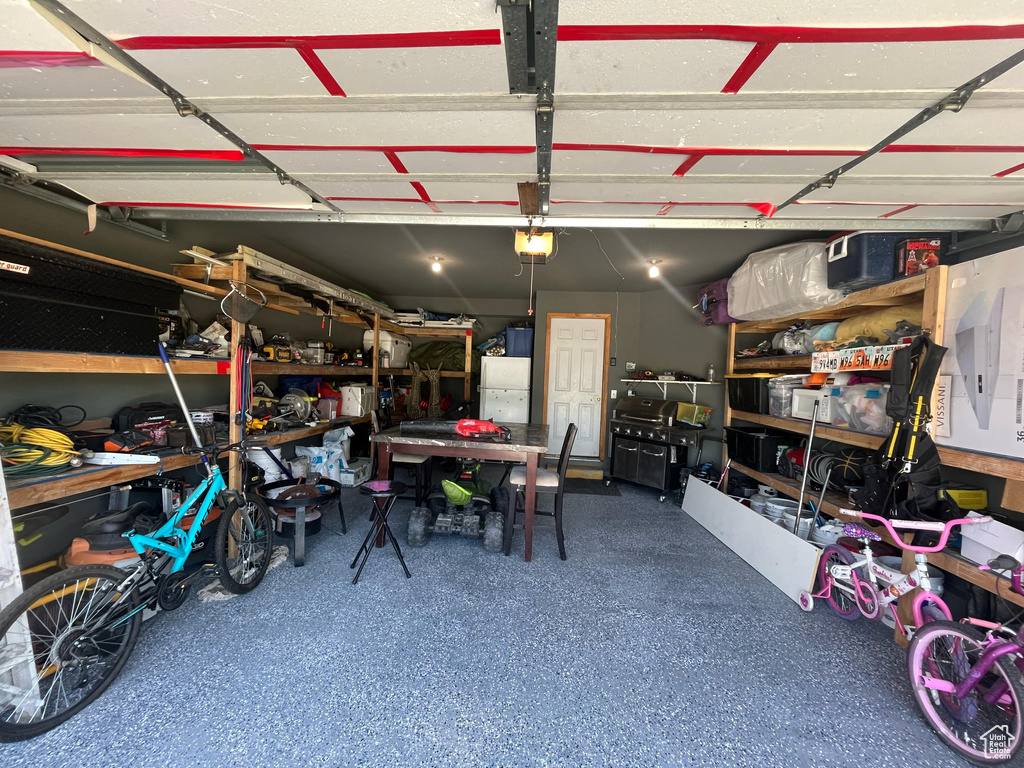 Garage featuring freestanding refrigerator, a garage door opener, and a workshop area