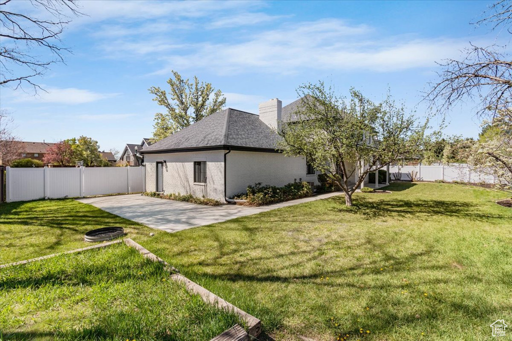 Rear view of house with a patio area, a fenced backyard, brick siding, and a lawn