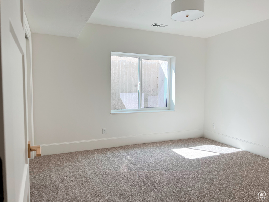 Carpeted spare room with visible vents and baseboards