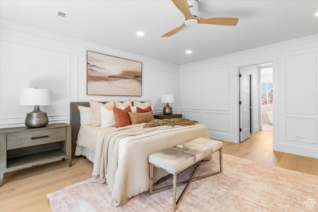 Bedroom featuring a decorative wall, light wood-type flooring, and crown molding