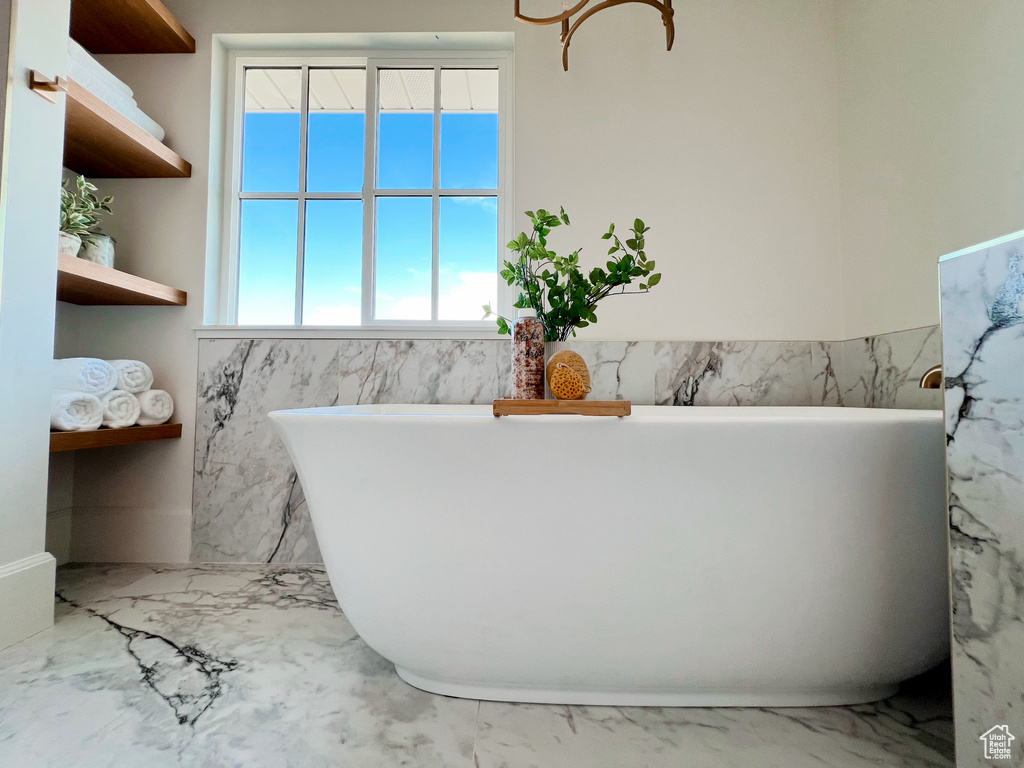 Full bath featuring a freestanding bath and marble finish floor