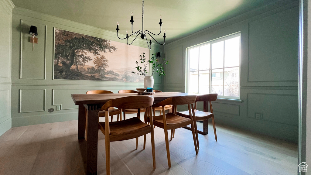 Dining area with a decorative wall, ornamental molding, an inviting chandelier, and a healthy amount of sunlight