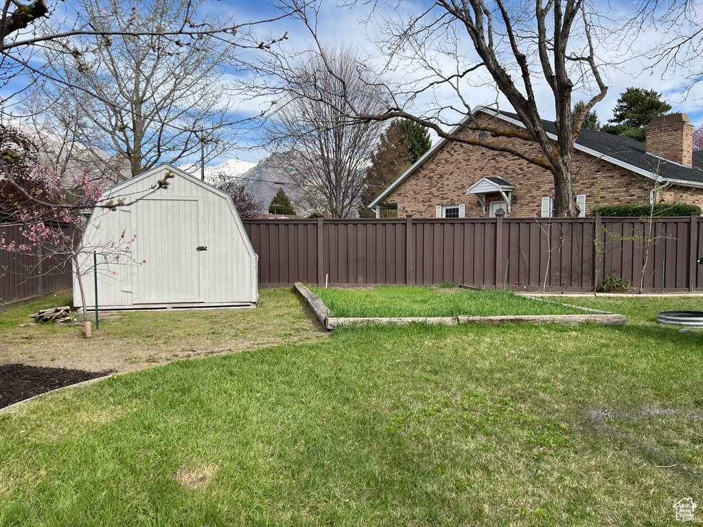View of yard featuring an outbuilding, a mountain view, fence, and a storage shed