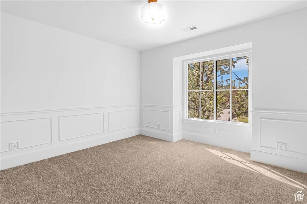 Spare room with carpet flooring, visible vents, and a wainscoted wall
