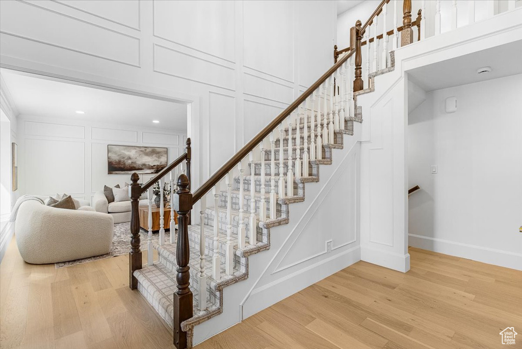 Stairway with a decorative wall, baseboards, recessed lighting, and wood finished floors