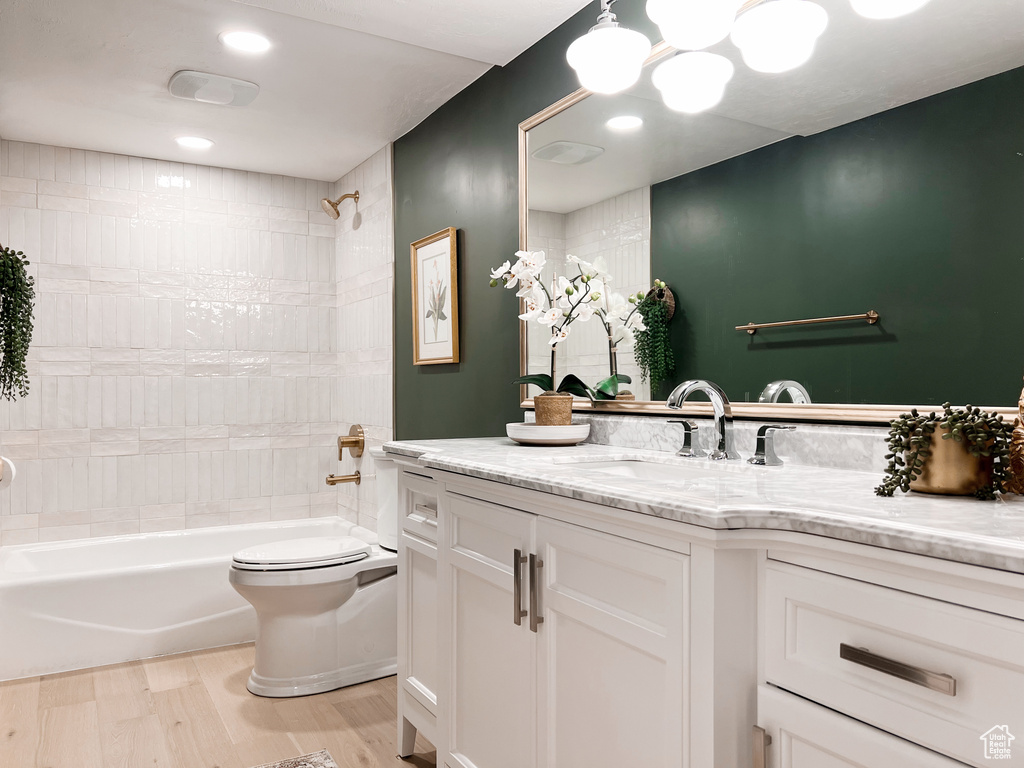 Bathroom with shower / bathtub combination, vanity, toilet, and wood finished floors