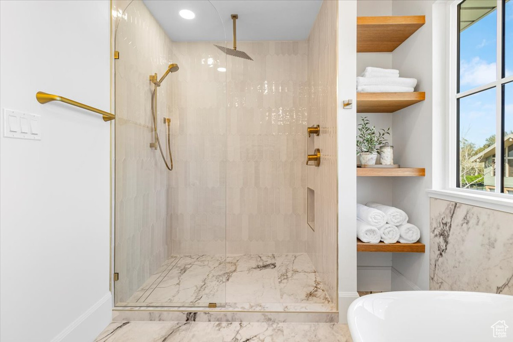 Bathroom featuring a shower stall, a freestanding tub, and marble finish floor