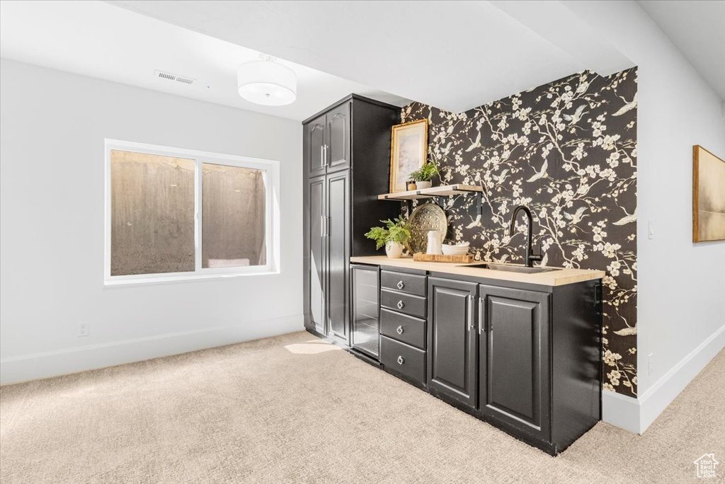 Bar featuring a sink, baseboards, wet bar, and light carpet