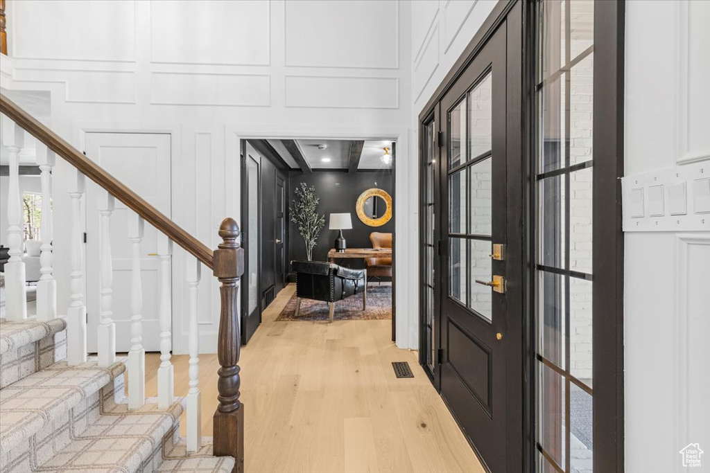 Foyer entrance with a decorative wall, light wood-style flooring, and stairs
