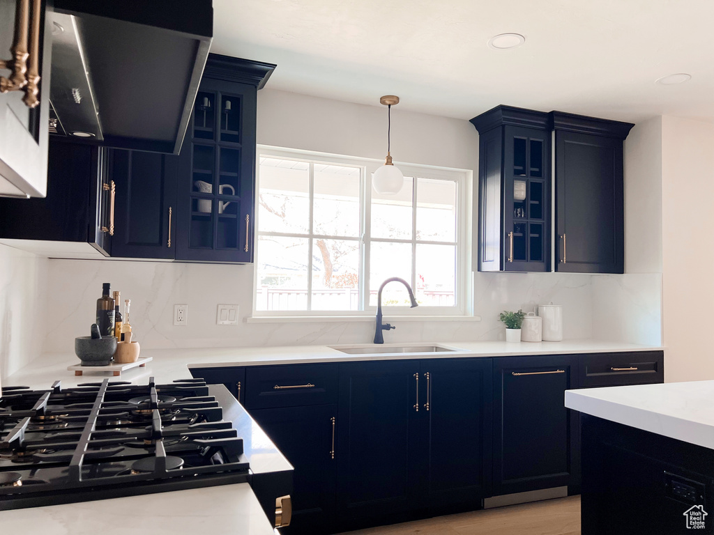 Kitchen featuring a sink, black gas cooktop, exhaust hood, and blue cabinets
