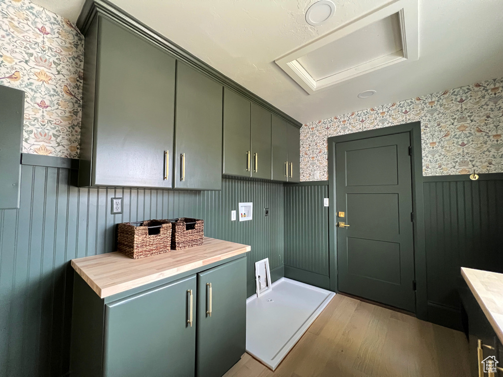 Interior space featuring light wood-type flooring, wallpapered walls, a wainscoted wall, and cabinet space