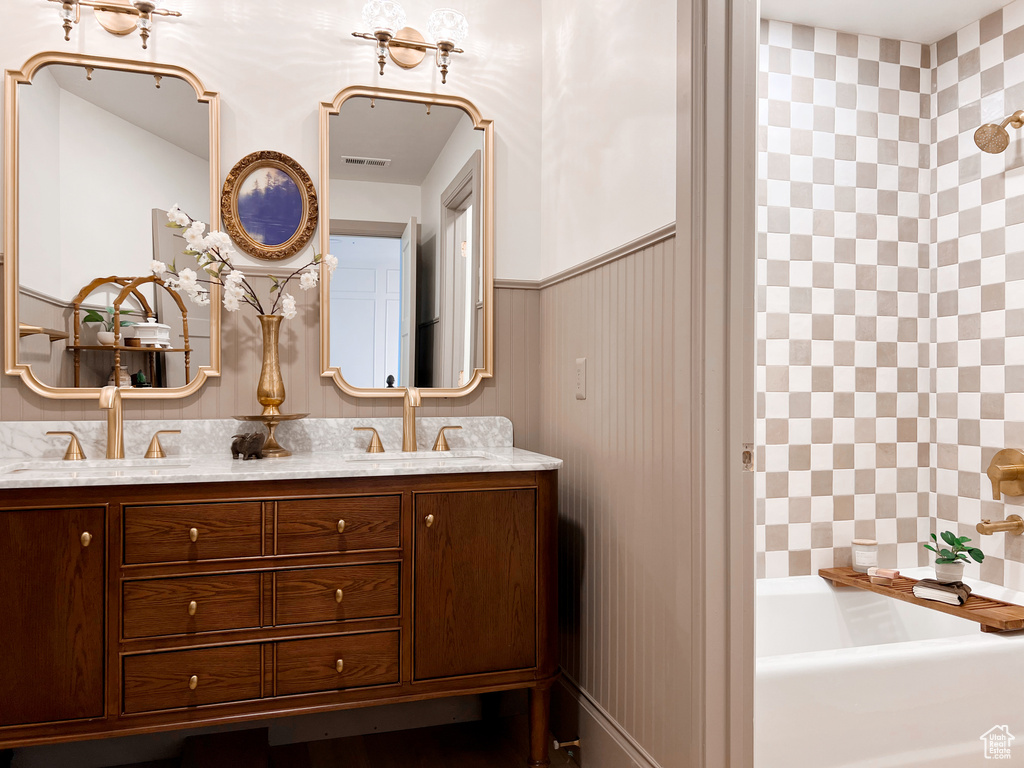 Full bath with a sink, walk in shower, double vanity, and a tub
