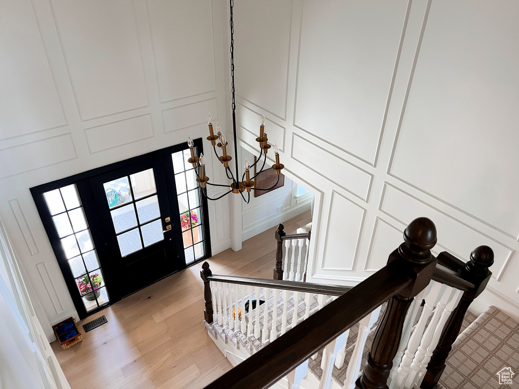 Entrance foyer featuring a decorative wall, visible vents, light wood finished floors, and an inviting chandelier