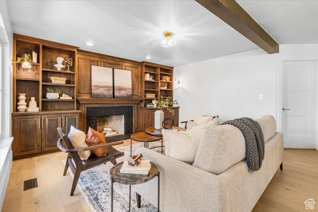 Living room featuring light wood-type flooring, a fireplace, visible vents, and recessed lighting