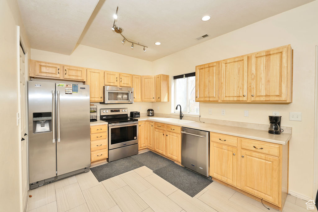 Kitchen with visible vents, appliances with stainless steel finishes, light countertops, a sink, and light brown cabinets