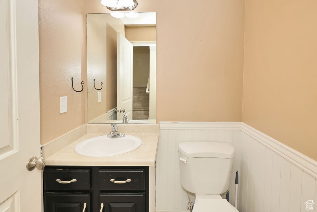 Half bath featuring toilet, a wainscoted wall, and vanity