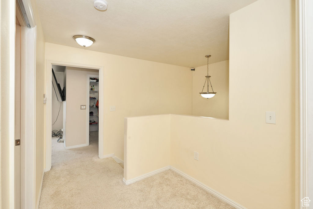 Corridor with light colored carpet and baseboards