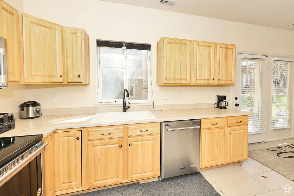 Kitchen featuring light countertops, a sink, light brown cabinets, and stainless steel appliances