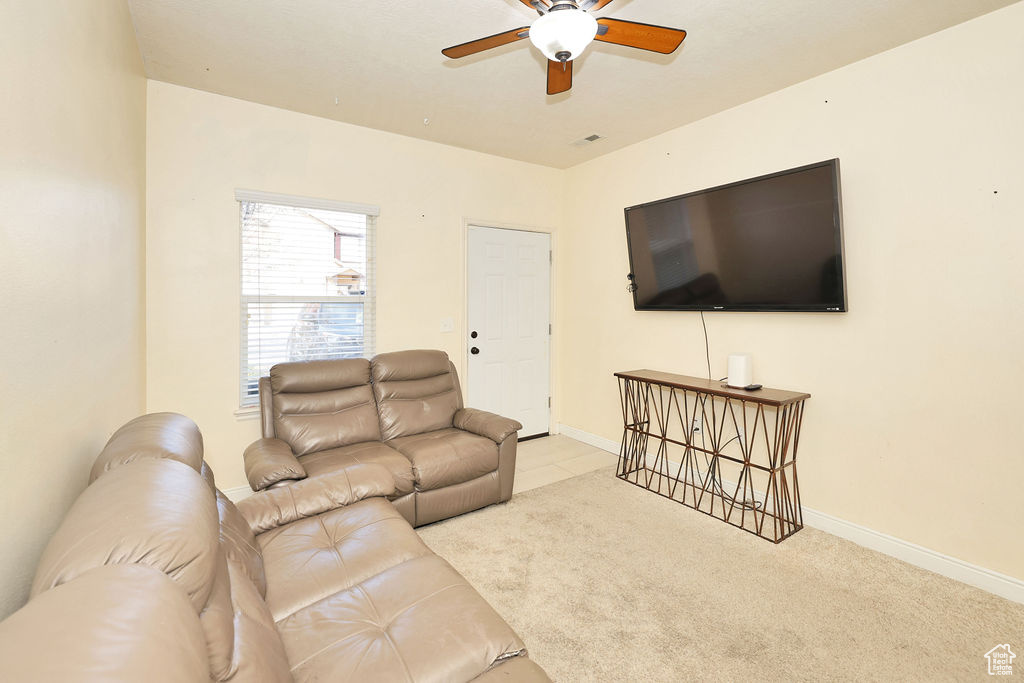 Carpeted living room featuring baseboards and a ceiling fan