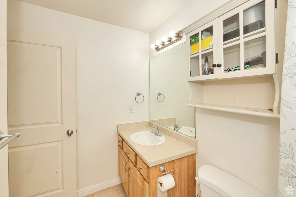 Bathroom featuring toilet, tile patterned floors, vanity, and baseboards