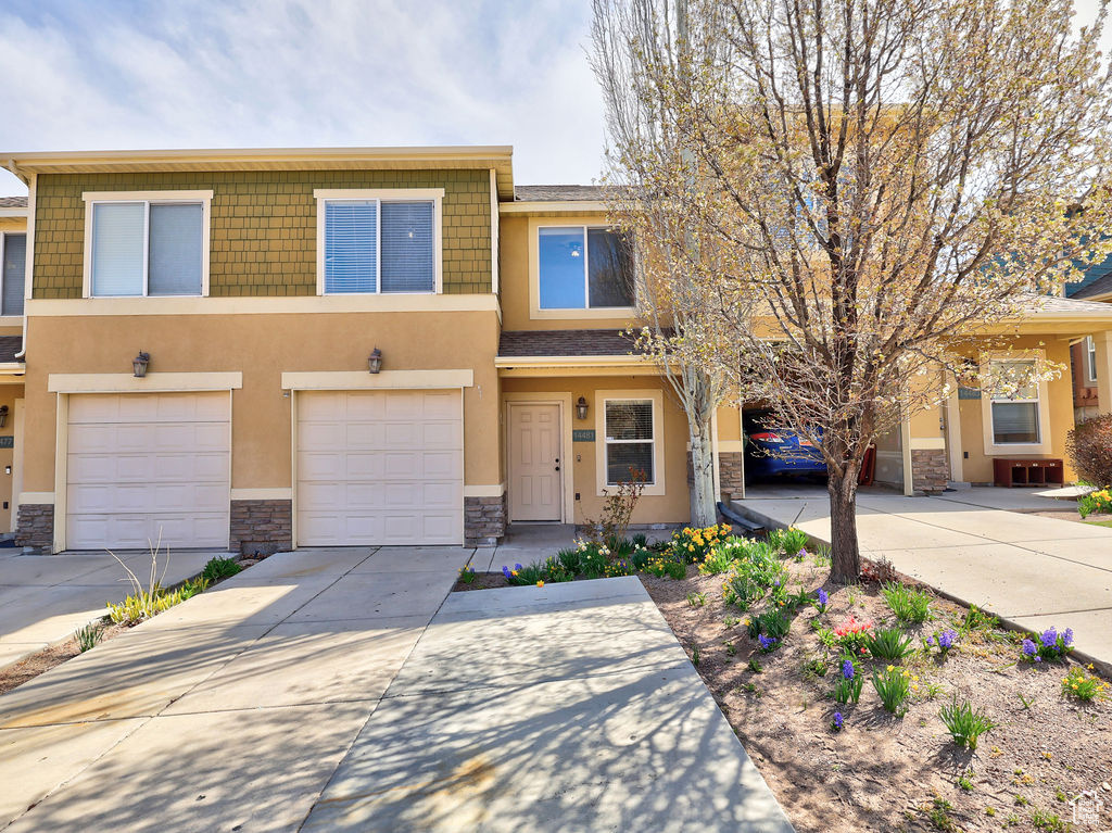 View of property with driveway, stone siding, and stucco siding