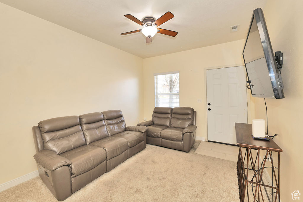 Carpeted living room with visible vents, baseboards, and ceiling fan