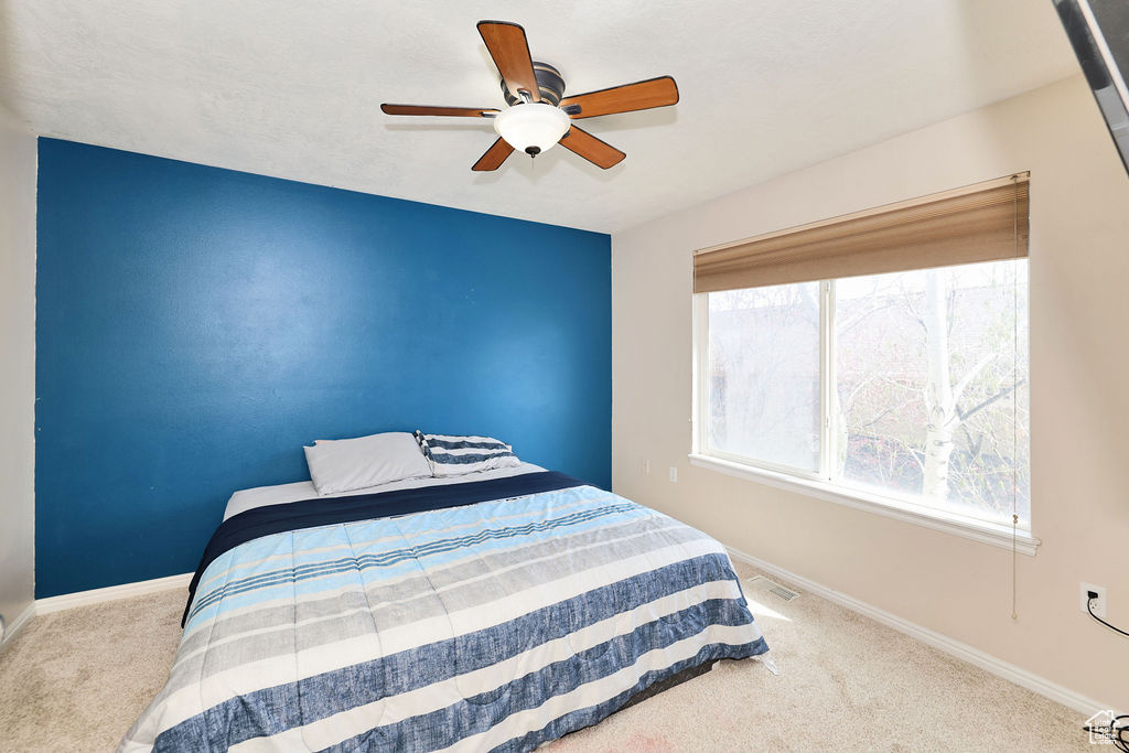 Carpeted bedroom featuring ceiling fan, baseboards, and visible vents
