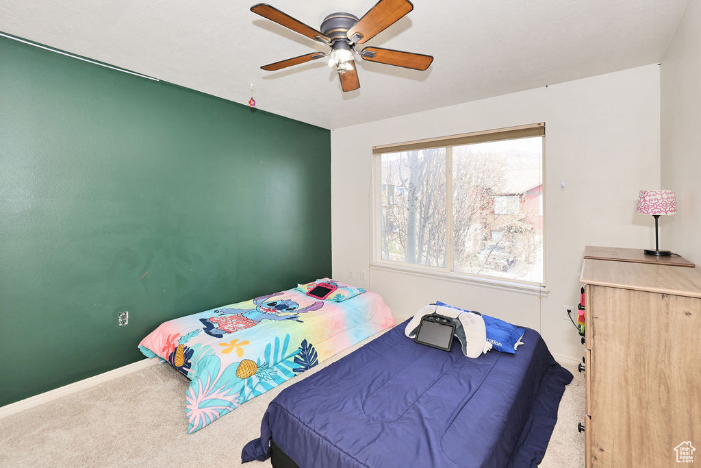 Carpeted bedroom featuring ceiling fan and baseboards