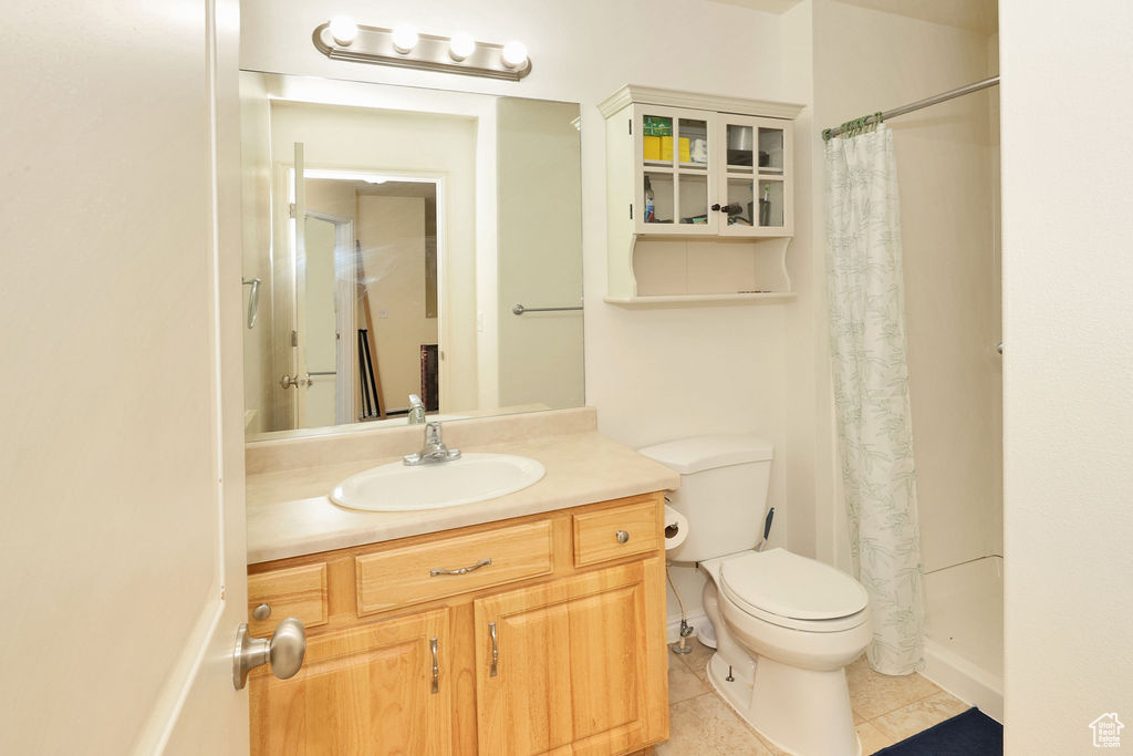 Bathroom featuring a shower with shower curtain, tile patterned flooring, vanity, and toilet