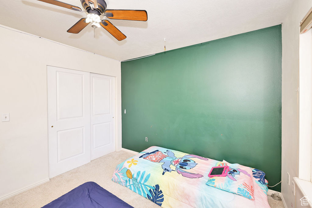 Carpeted bedroom featuring baseboards, a closet, and a ceiling fan