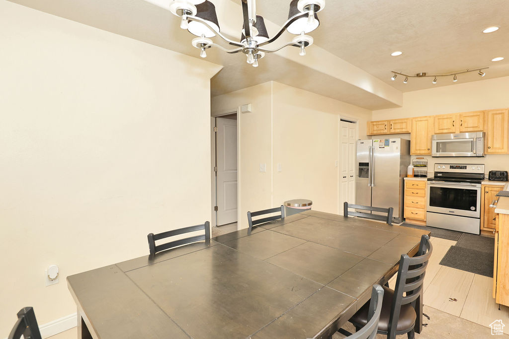 Dining area featuring a notable chandelier, rail lighting, baseboards, and recessed lighting