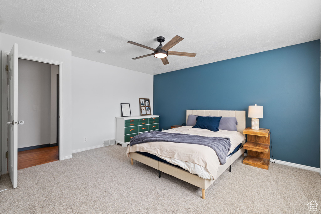 Bedroom with visible vents, a ceiling fan, carpet, and a textured ceiling