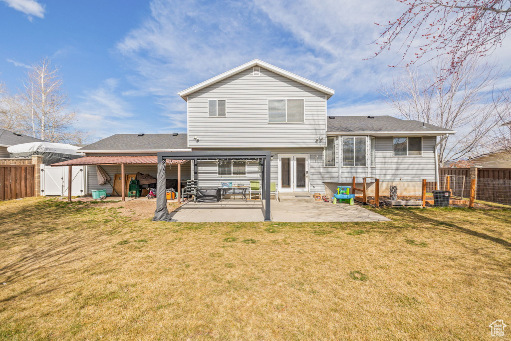 Back of house with a shingled roof, a yard, a fenced backyard, a patio, and a gate