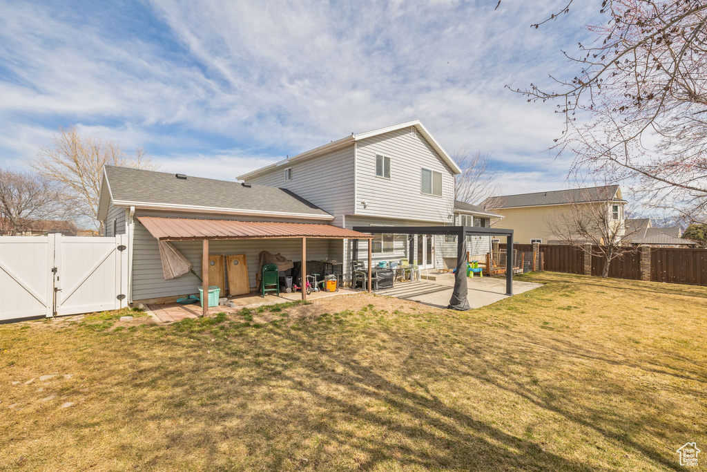 Back of property with a patio area, a yard, a fenced backyard, and a gate