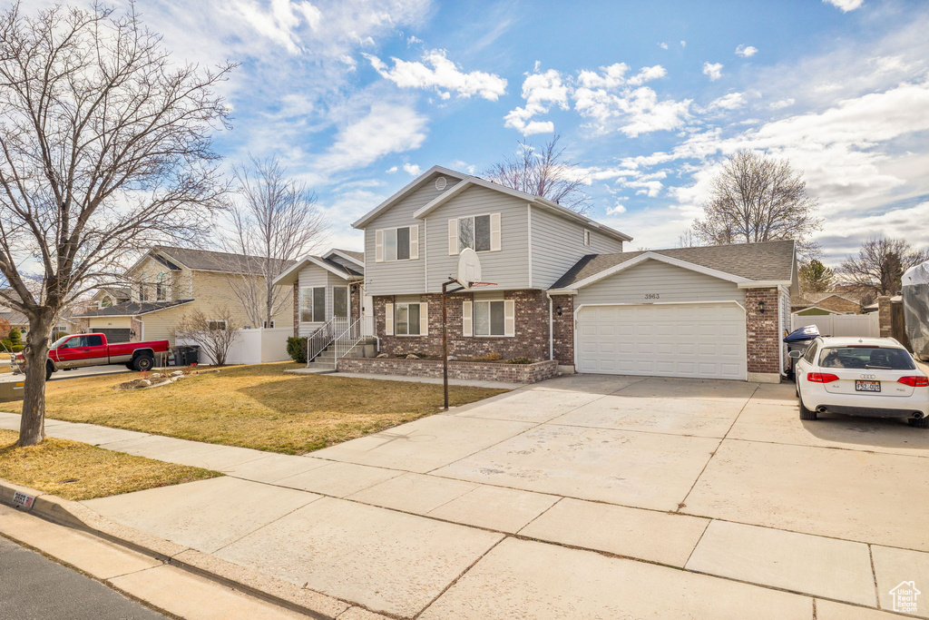 Traditional-style home with a front yard, an attached garage, fence, brick siding, and driveway