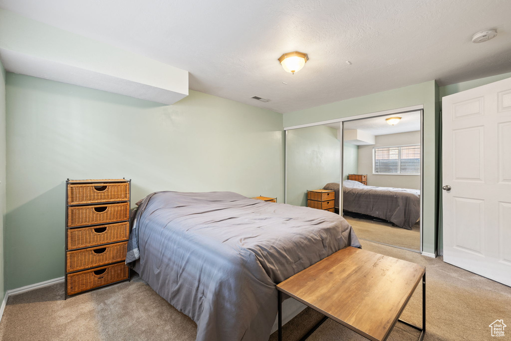 Bedroom featuring light carpet, visible vents, a closet, and baseboards