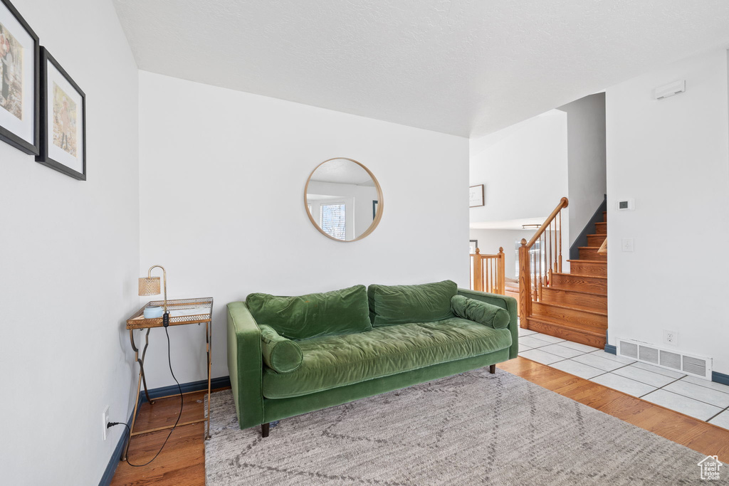 Living area featuring wood finished floors, baseboards, visible vents, and stairs