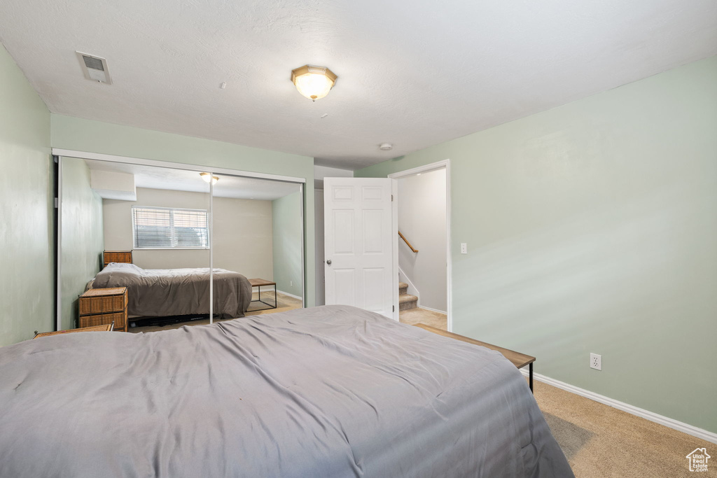 Bedroom with a closet, light colored carpet, baseboards, and visible vents