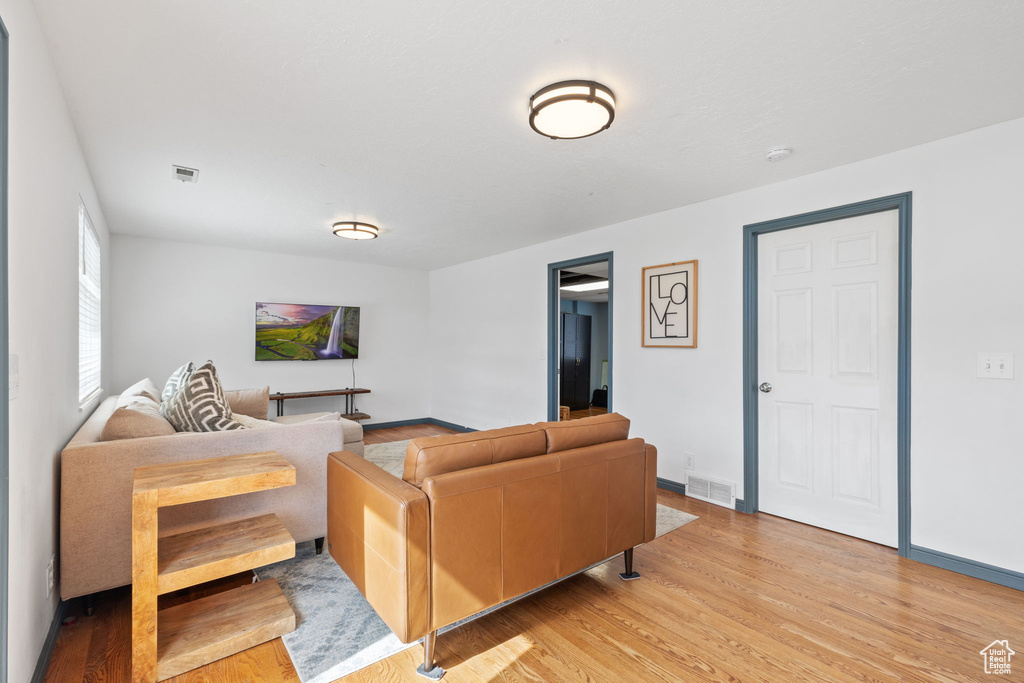 Living room with light wood finished floors, baseboards, and visible vents