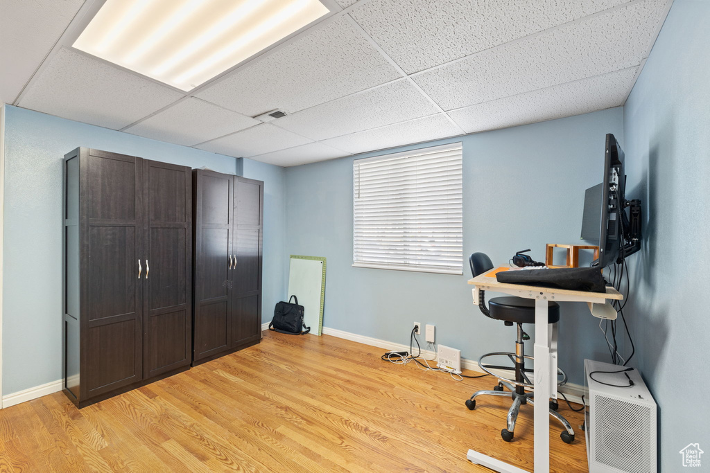Office space featuring light wood-style floors, baseboards, a drop ceiling, and visible vents