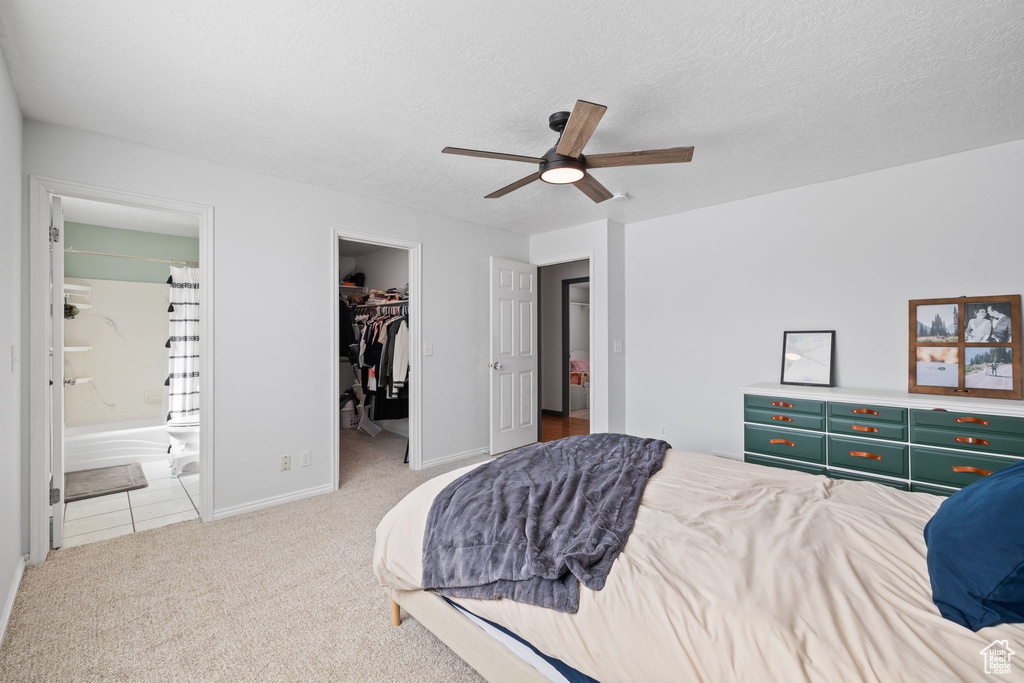 Carpeted bedroom featuring ensuite bathroom, a closet, baseboards, a spacious closet, and a textured ceiling