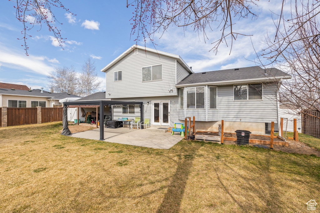 Back of property with a shingled roof, a yard, a patio area, and a fenced backyard