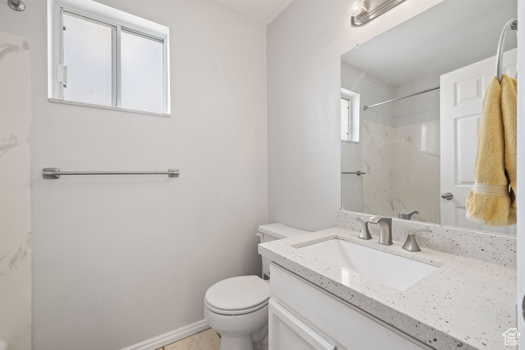 Full bathroom with vanity, a marble finish shower, toilet, and a healthy amount of sunlight