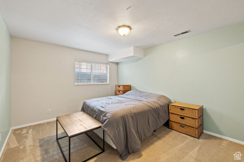 Bedroom with visible vents, light colored carpet, and baseboards