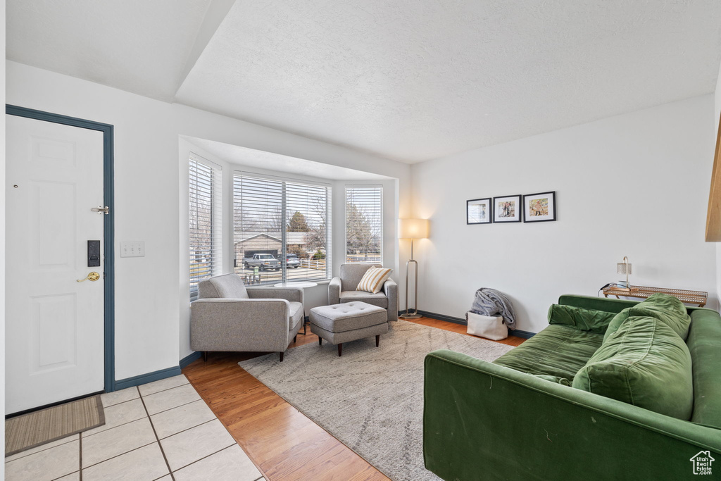 Living area featuring light tile patterned floors, baseboards, and a textured ceiling